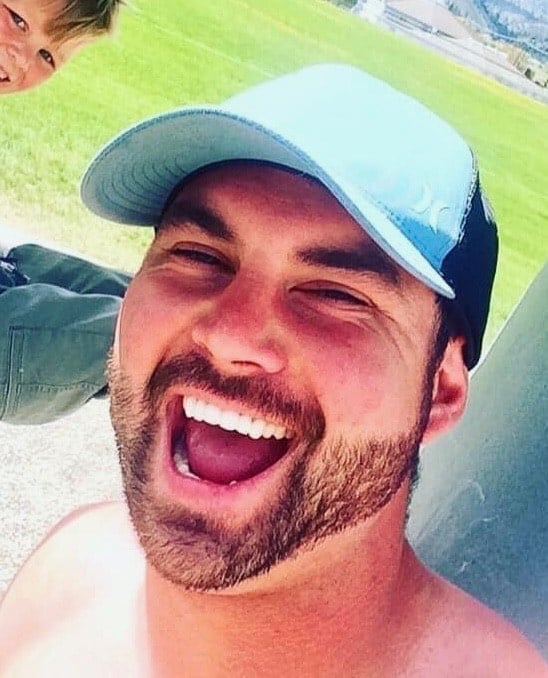 Profile photo of a smiling man with a black beard wearing a blue ball cap