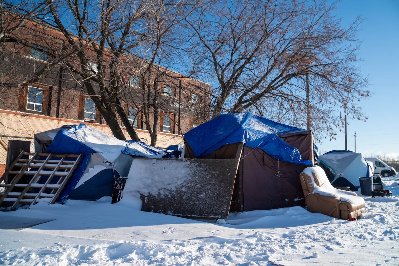 A cluster of tents and other structures are seen in a snowy field.