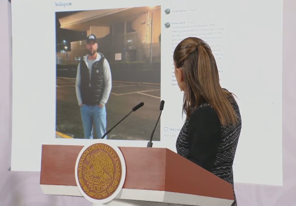 A woman points to the image of a man on a big screen