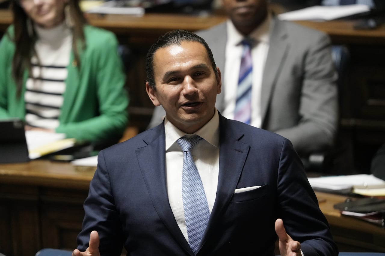 A man in a blue suit speaks during a government legislative session.