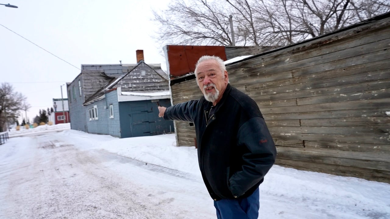 Man pointing across at a street.