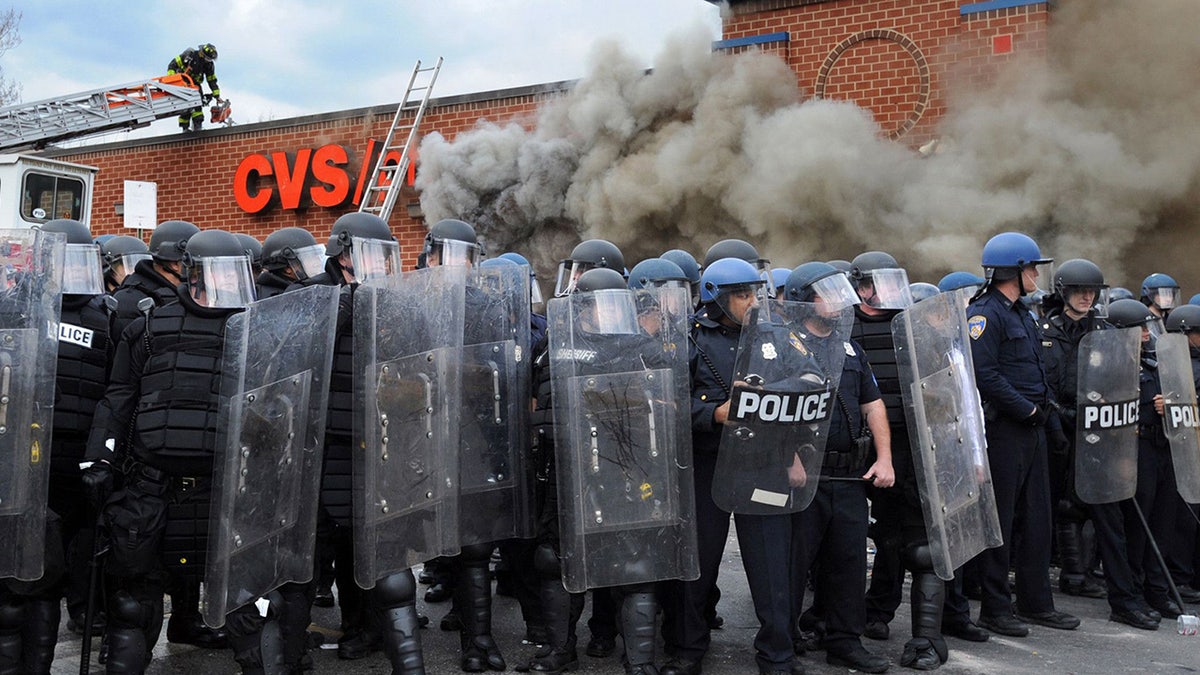 Looting and rioting in Baltimore, Maryland, with police in riot gear responding.