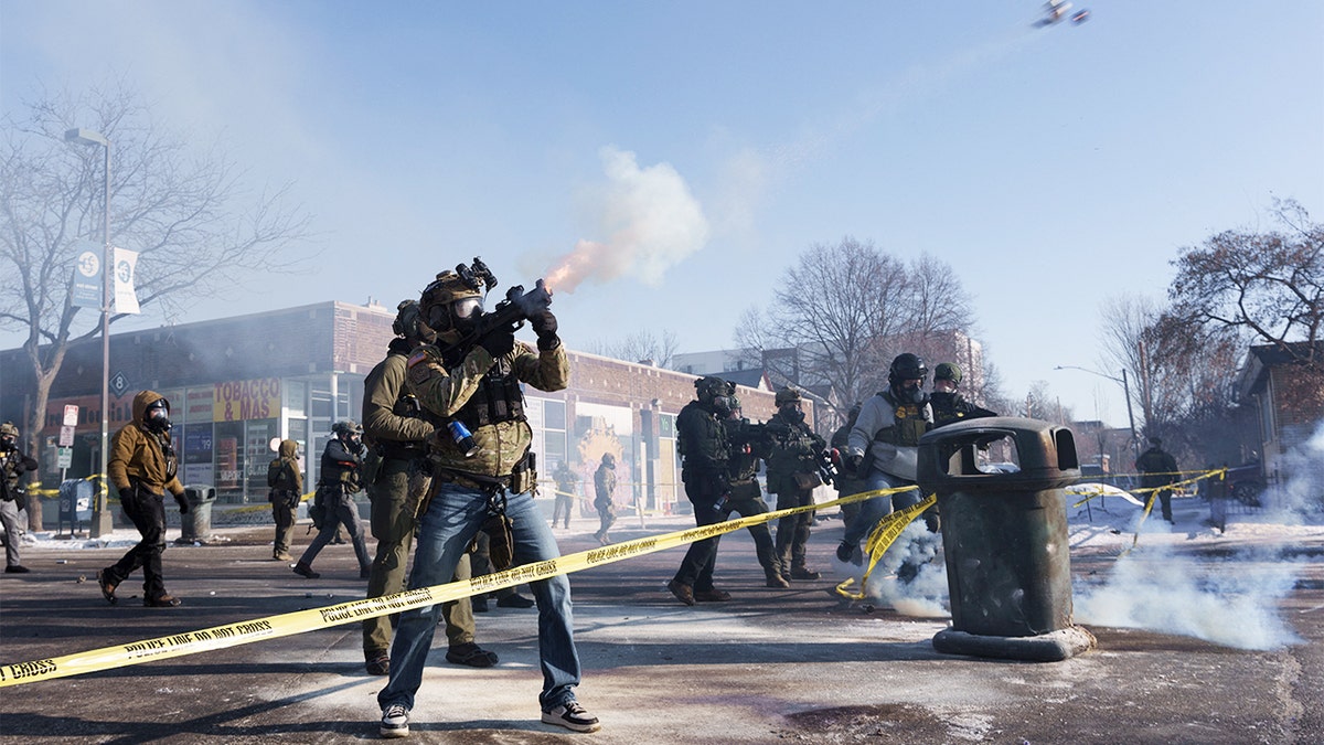 A federal officer fires a munition toward a group of demonstrators during a tense confrontation on a Minneapolis street.
