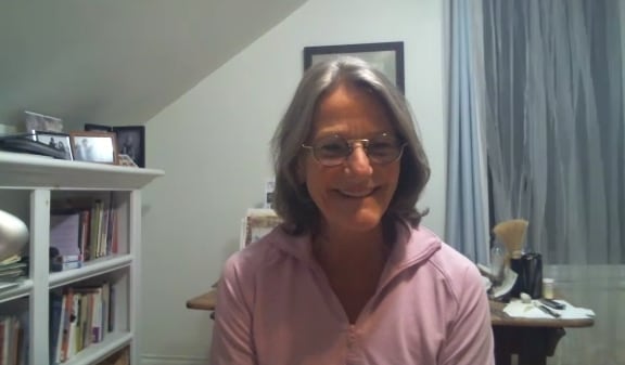 A woman in a purple jacket is smiling.