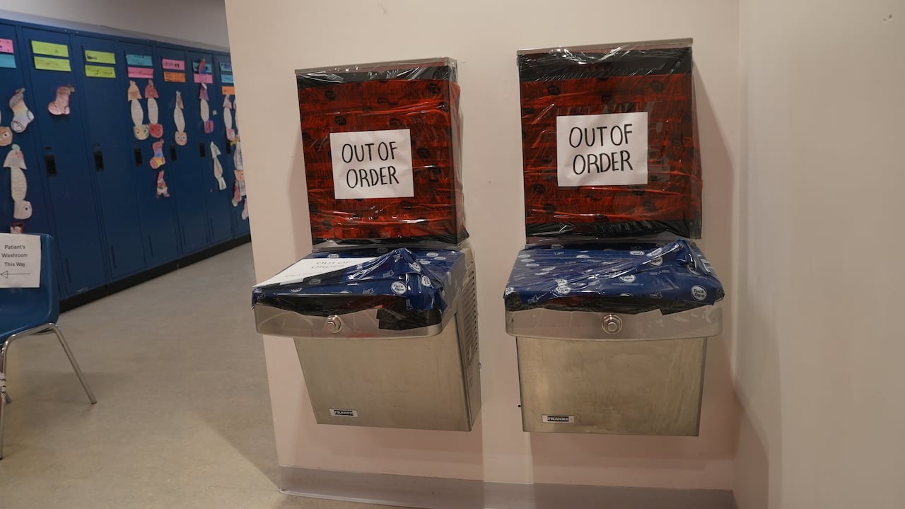 Drinking fountains at a school with out of order signs on them.