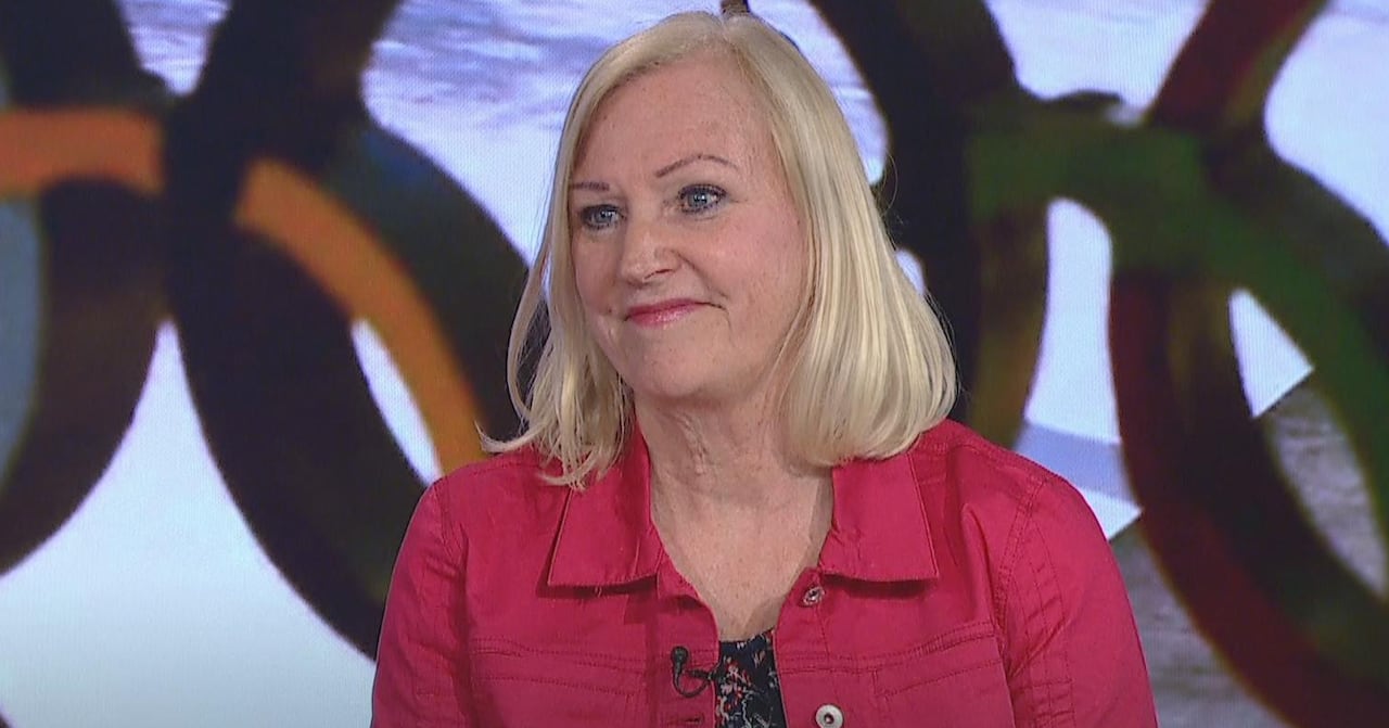 A woman sitting in front of the Olympic rings.