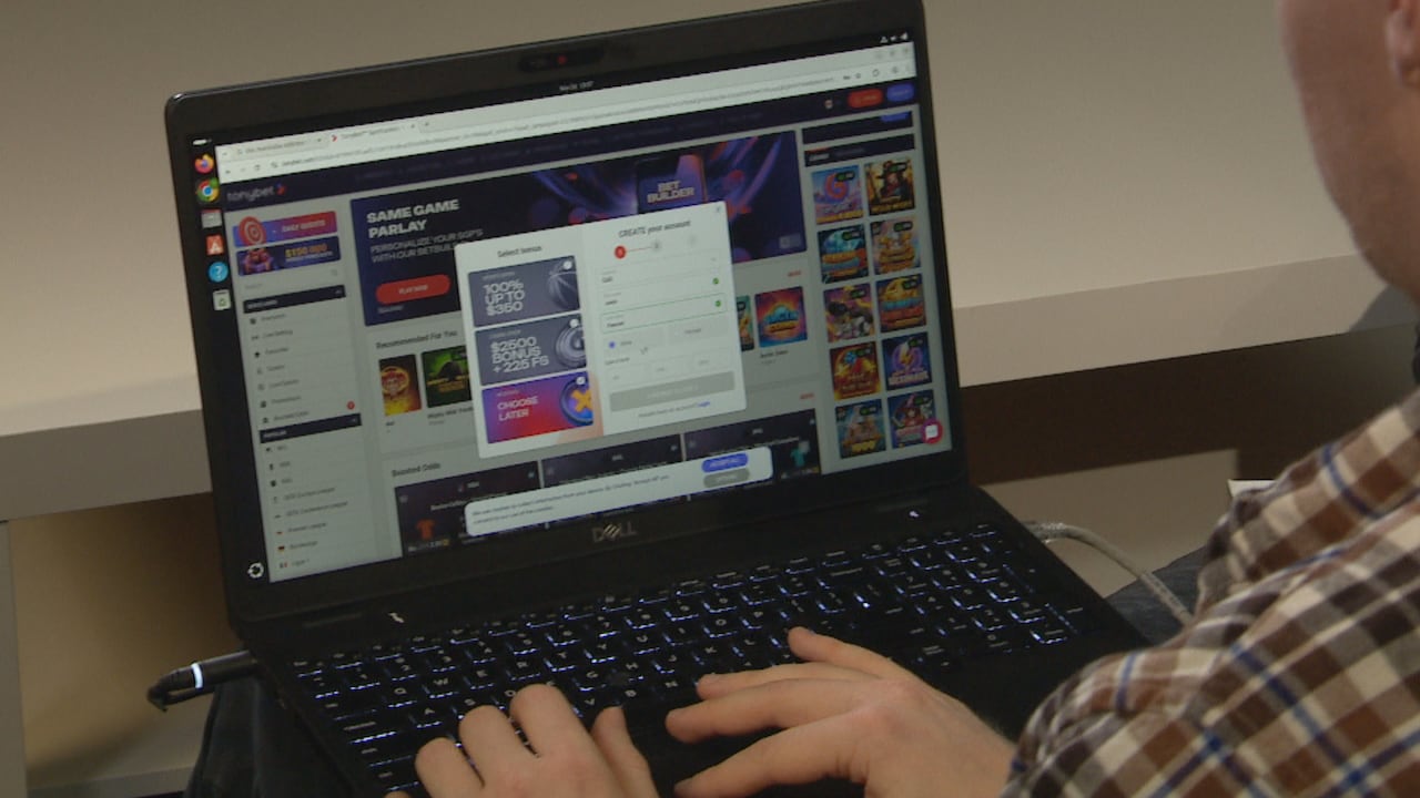 A laptop is open with a gambling website on the browser. A person's hands are on the keyboard.