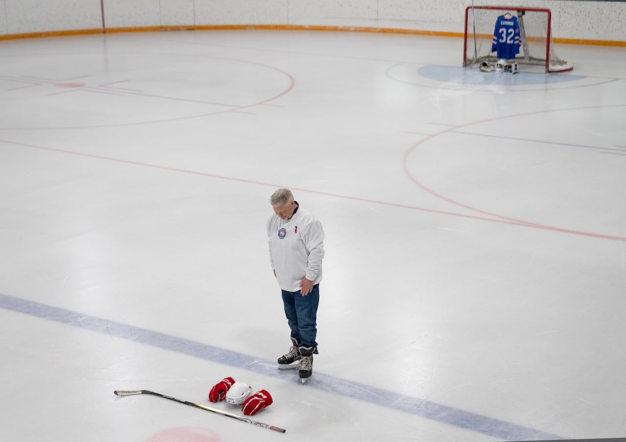 Chris Wright looks at his son's stick, helmet and gloves on the ice.