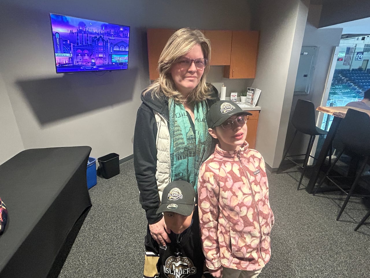 A woman stands with two children wearing Charlottetown Islanders hats. 