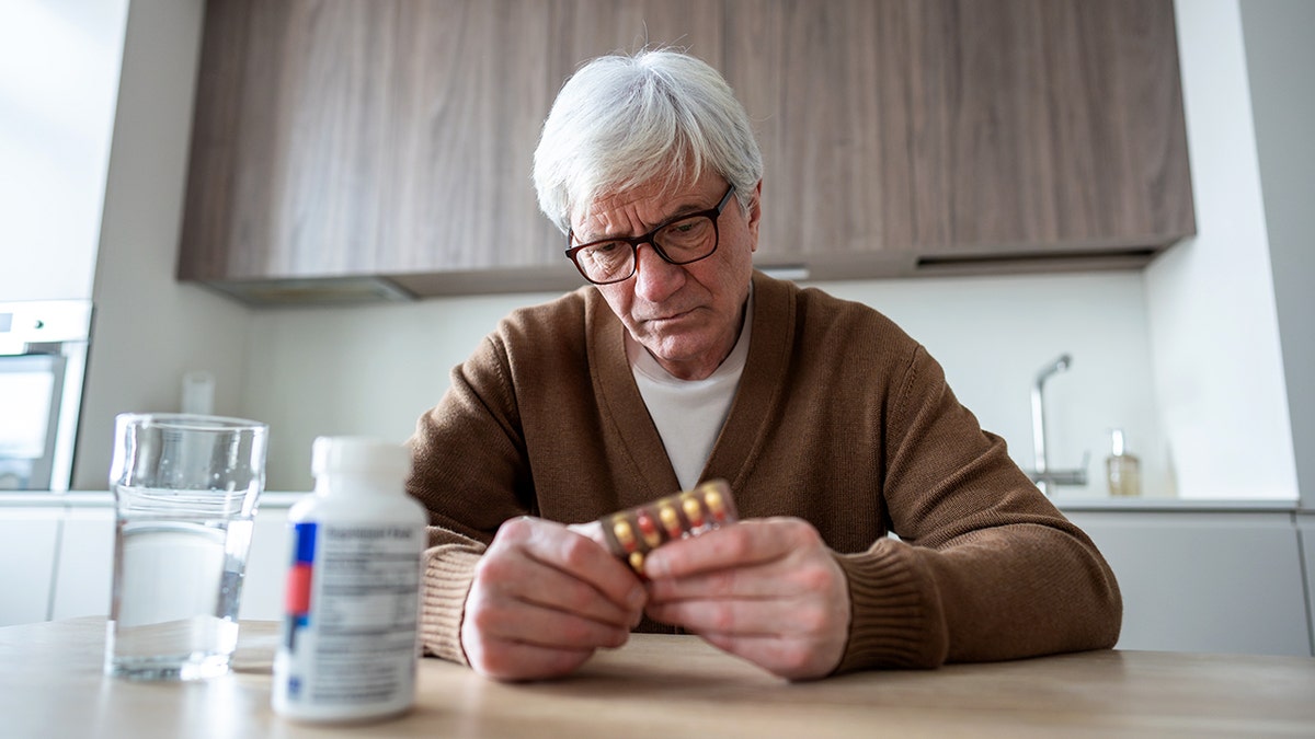 Frustrated man takes daily medication pile.