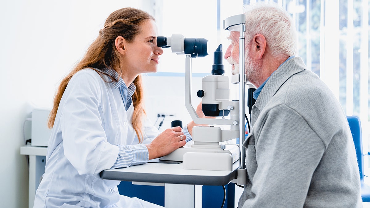Female optometrist examining an older man’s eyes