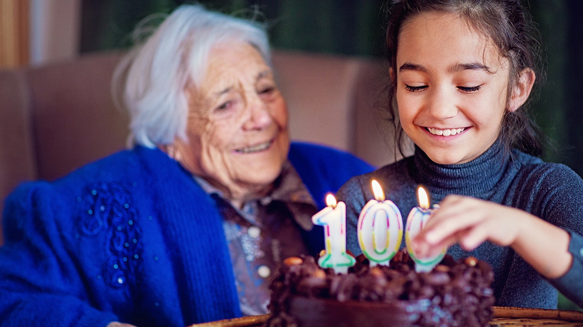 grandma and granddaughter 100th birthday cake with candles