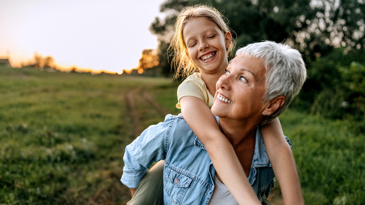 Grandmother carrying her granddaughter on back outdoors