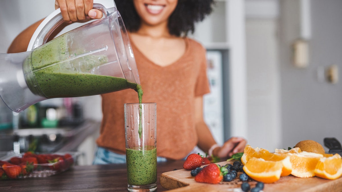 woman prepares smoothie with healthy foods