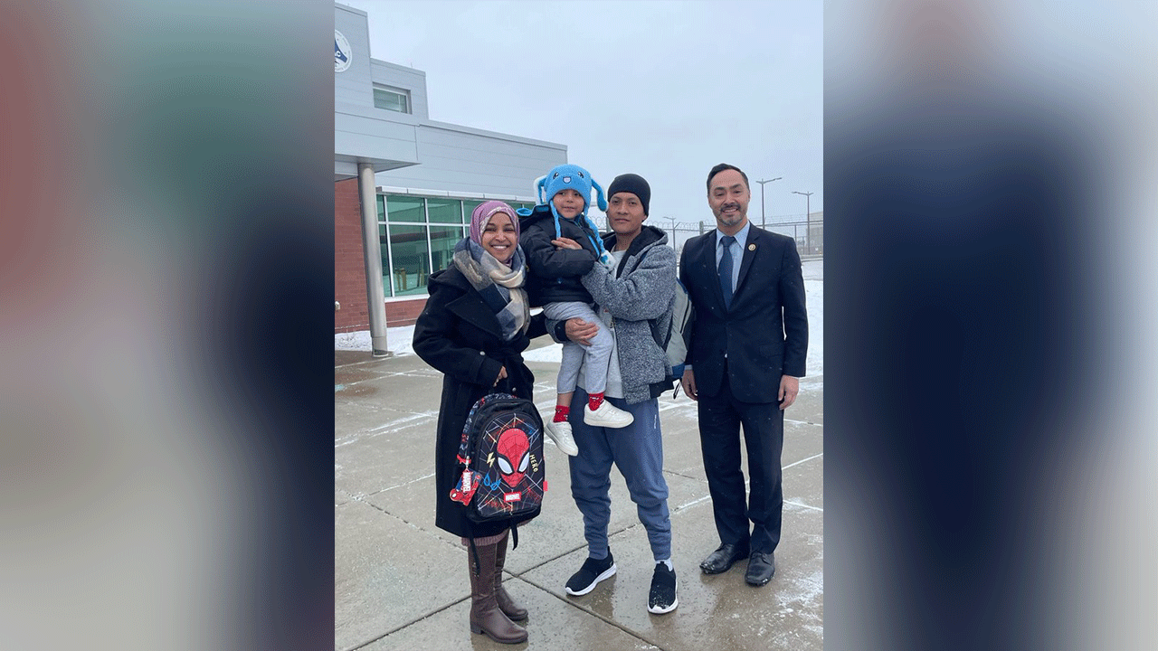 Four people stand outdoors, one holding a child.