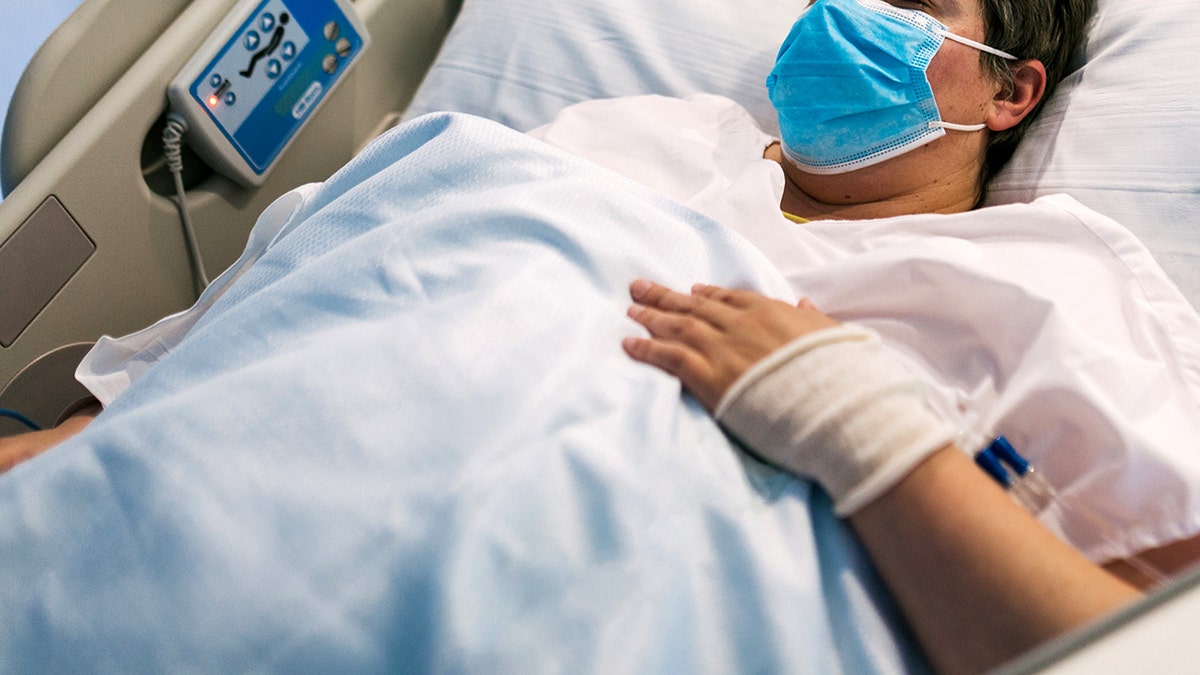 Overweight female patient in face mask lying on modern hospital bed