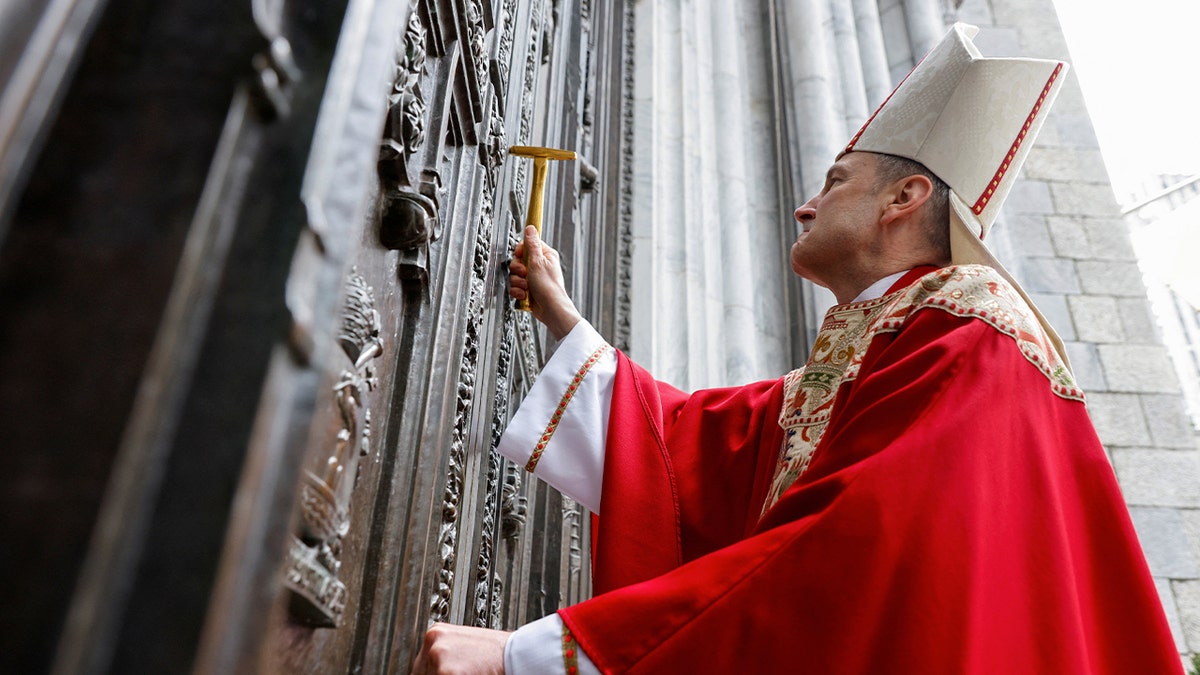 Archbishop Ronald Hicks knocks on door of St. Patrick's Cathedral with a metal hammer