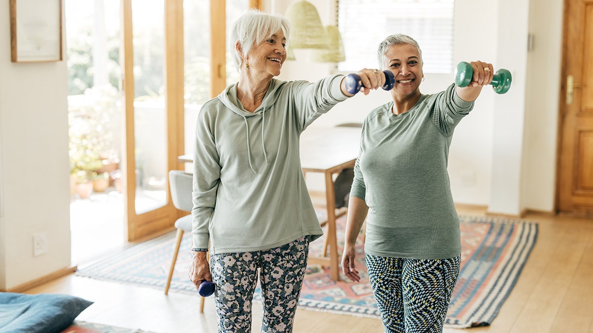 two senior women lift light dumbbells