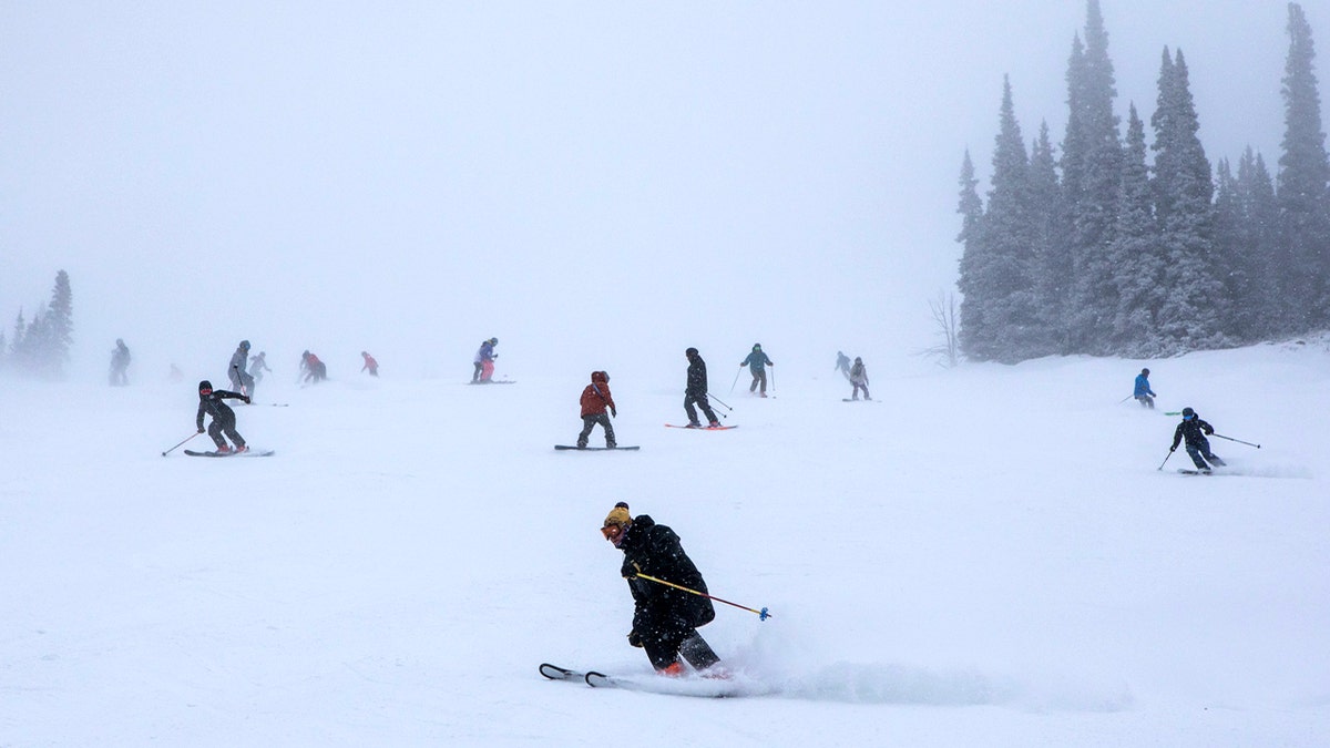 Skiers and snowboarders ride down a snow-covered slope at Jackson Hole Mountain Resort.