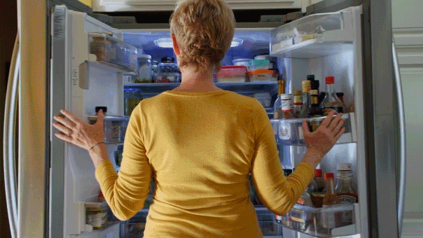 Woman looking for a snack in fridge - food cravings