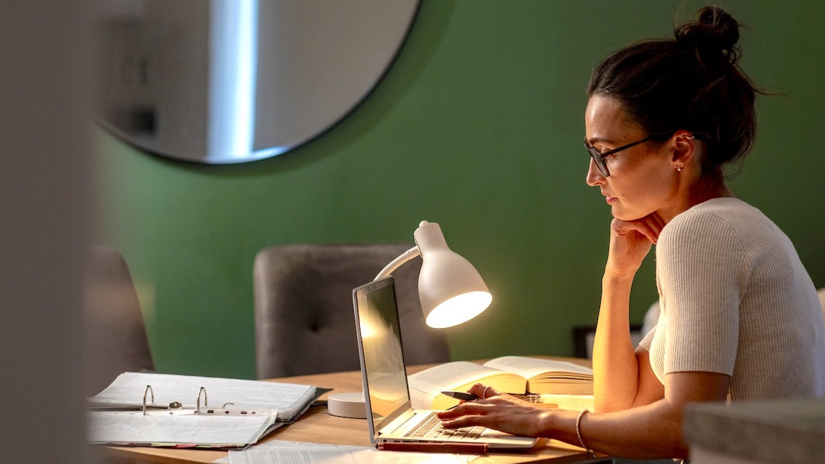 Woman on laptop using desk lamp