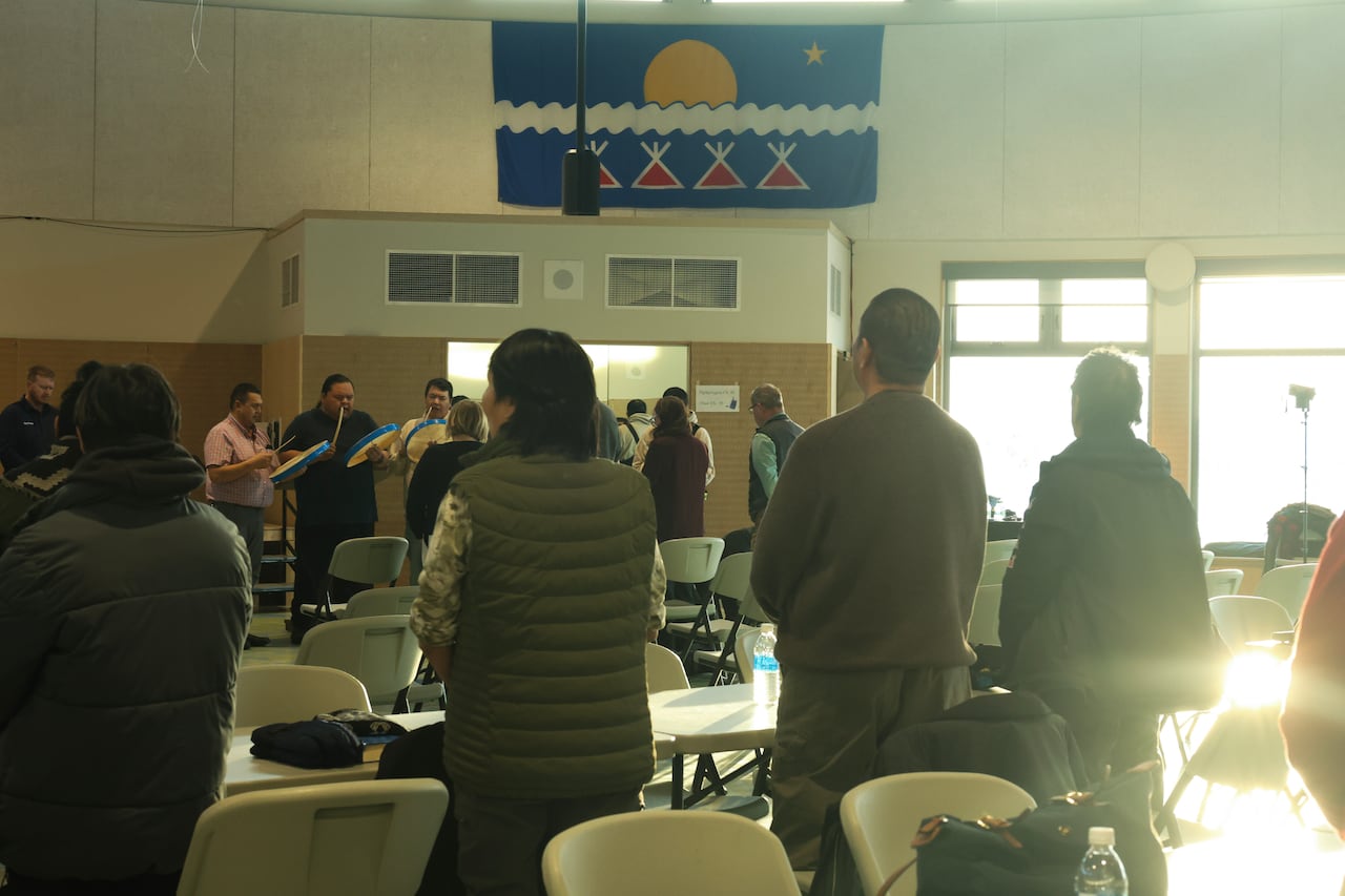 People stand as men perform a drum song