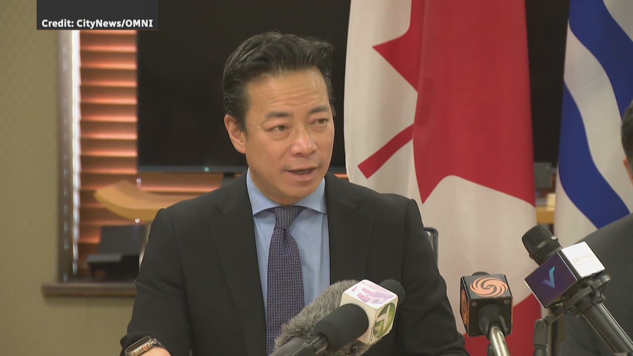 An East Asian man speaks at a podium.