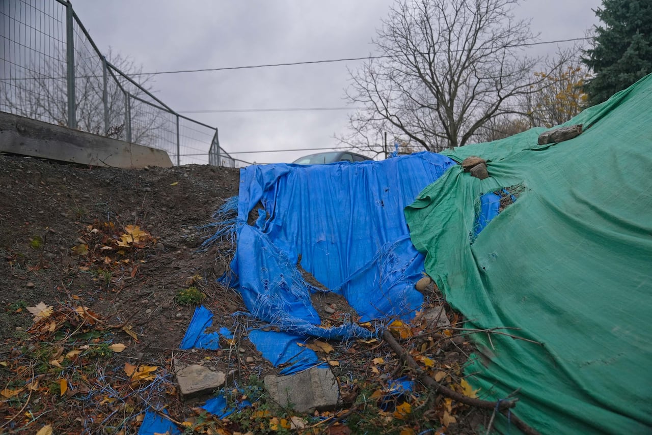 A blue tarp covers partly covers an excavated area in a yard.