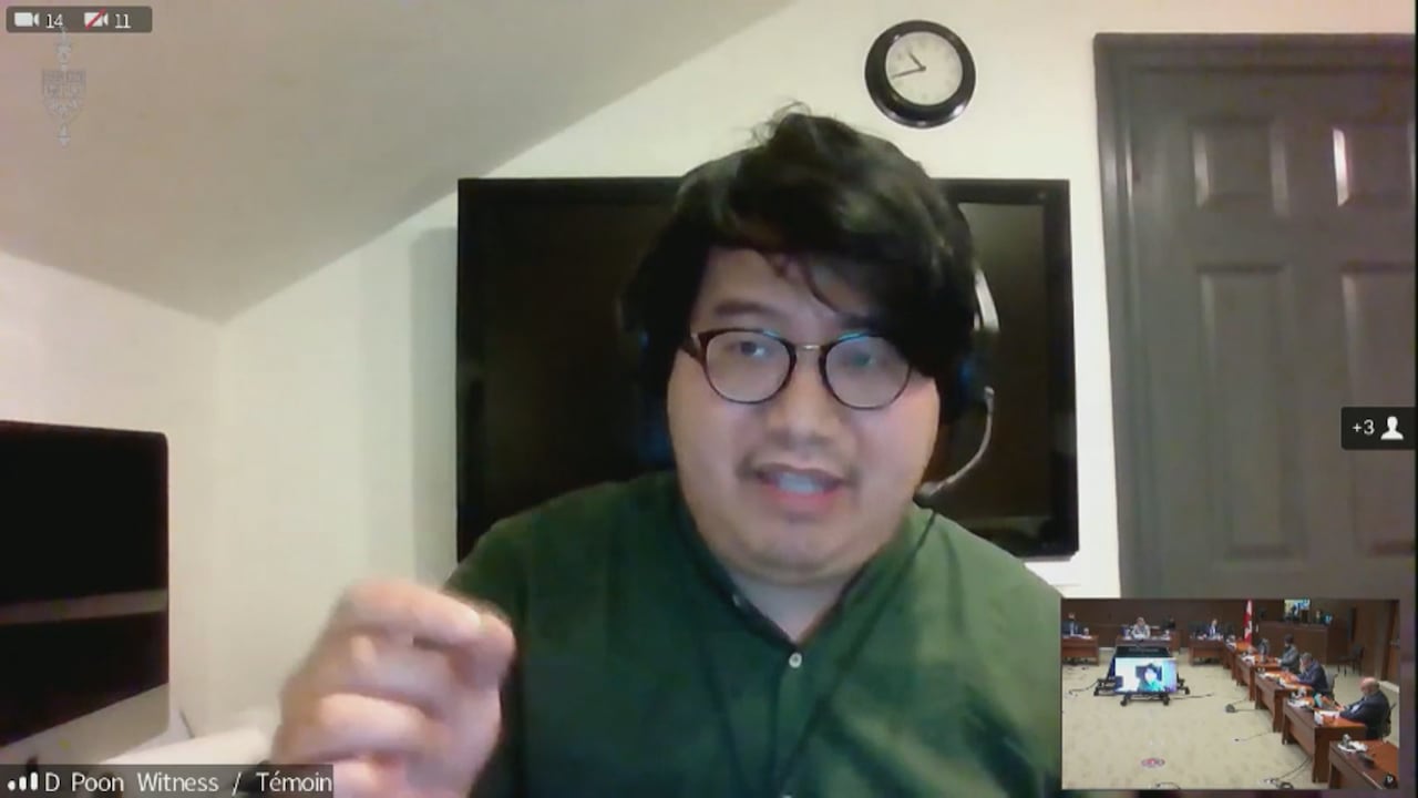 A screenshot of an Asian man with glasses in a green dress shirt addressing a government committee over a virtual call.