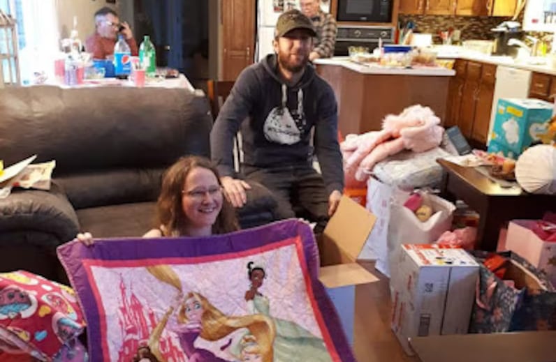 Young woman holds up Disney princess quilt as a baby shower gift