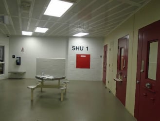 The inside of a jail is seen with white walls and red doors