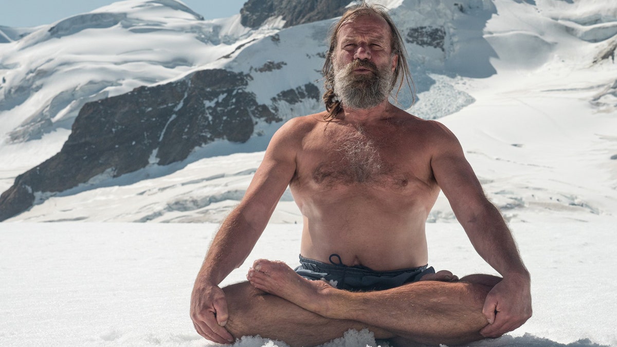 wim hof sits cross-legged in snow