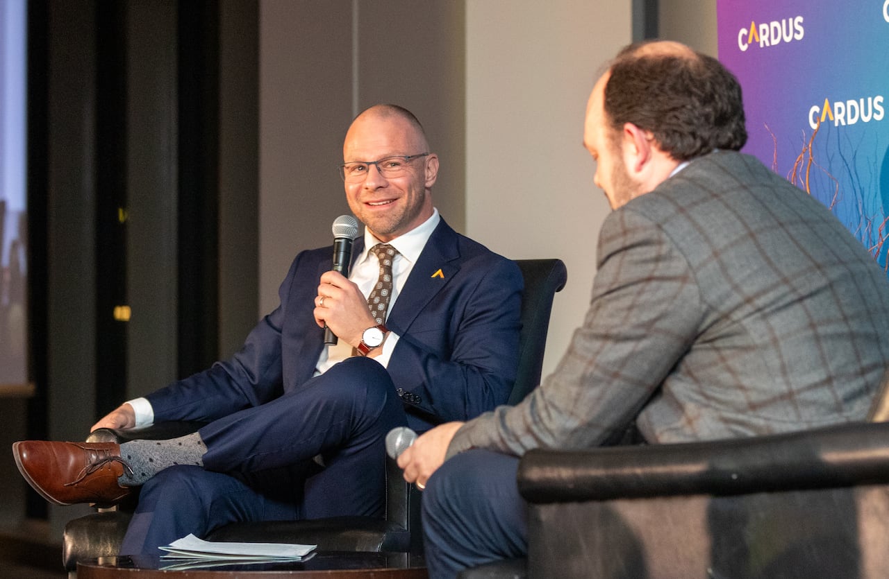 A man speaks into a microphone and smiles