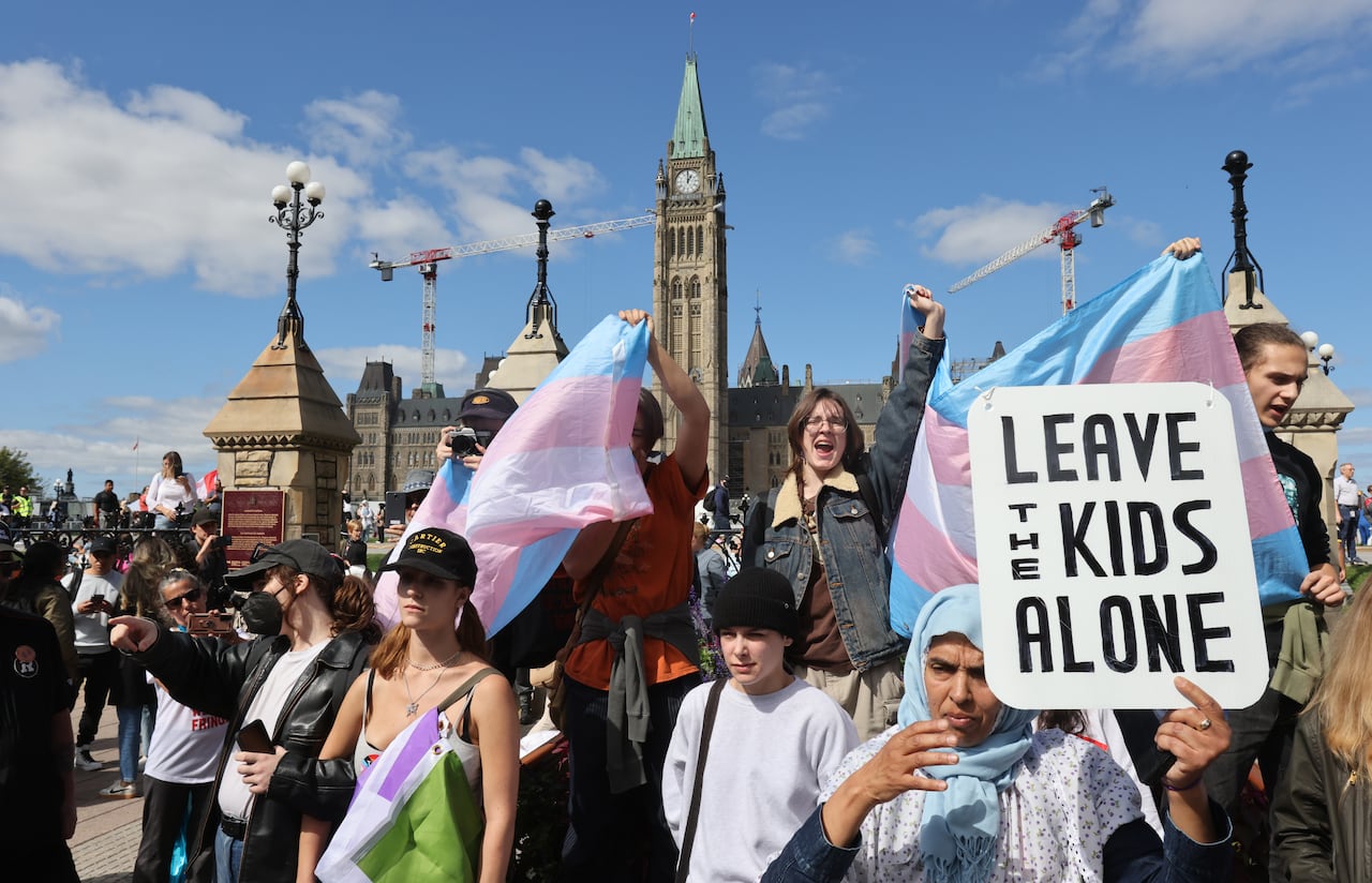 A woman holds a sign that reads Leave the kids alone. 