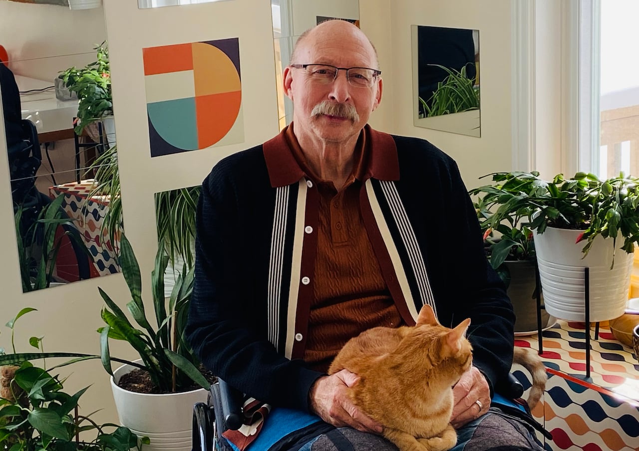 A man sits in a chair holding a cat.