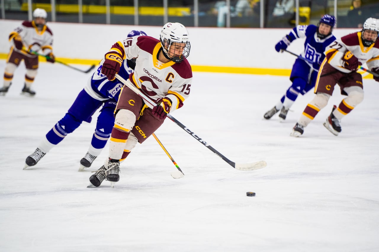 A hockey player skates with the puck.