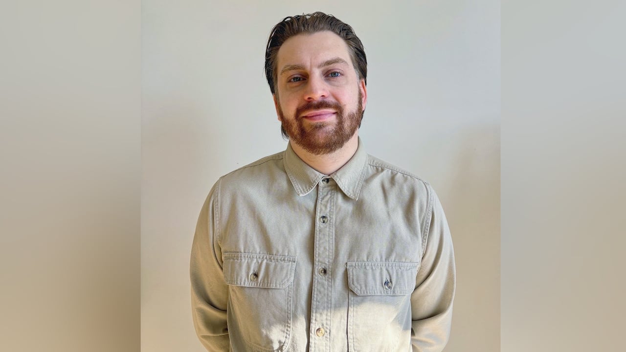 A man is seen wearing a cream shirt against a white background.