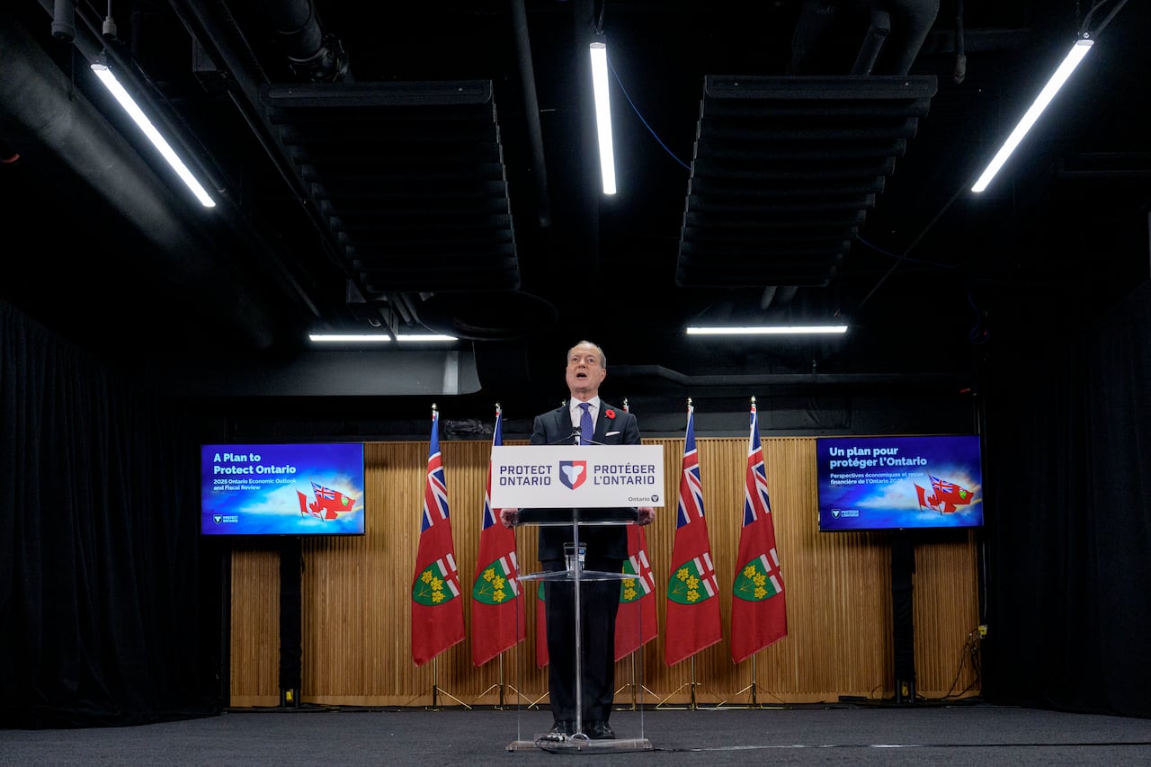 A man stands at a podium with a sign pasted to it that reads "Protect Ontario".