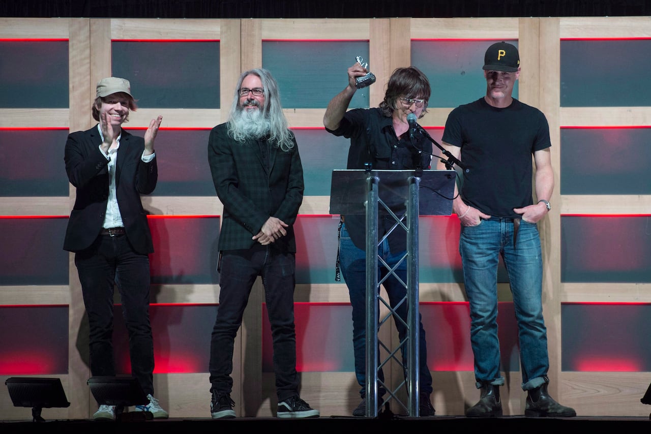 The four members of Sloan are shown on stage in a 2018 photo accepting a music industry award.