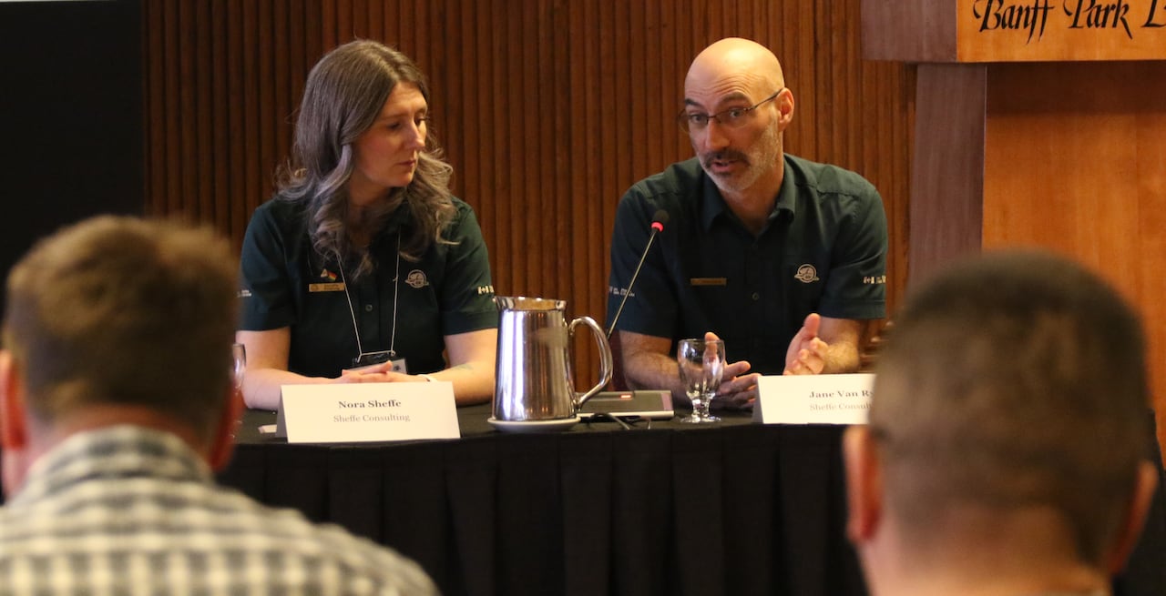 Two people speak to a group of people.