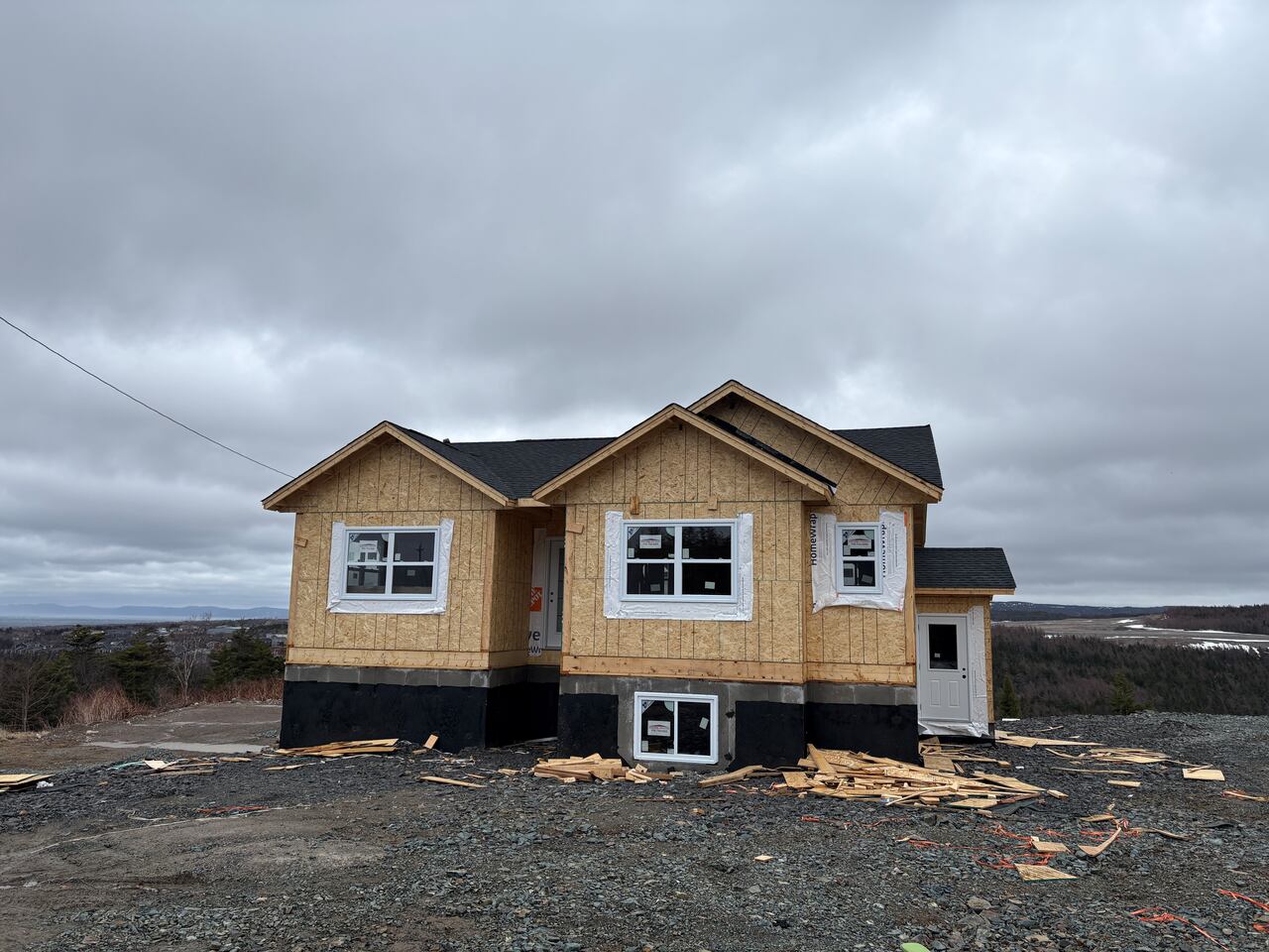 A house under construction on a gravel lot.