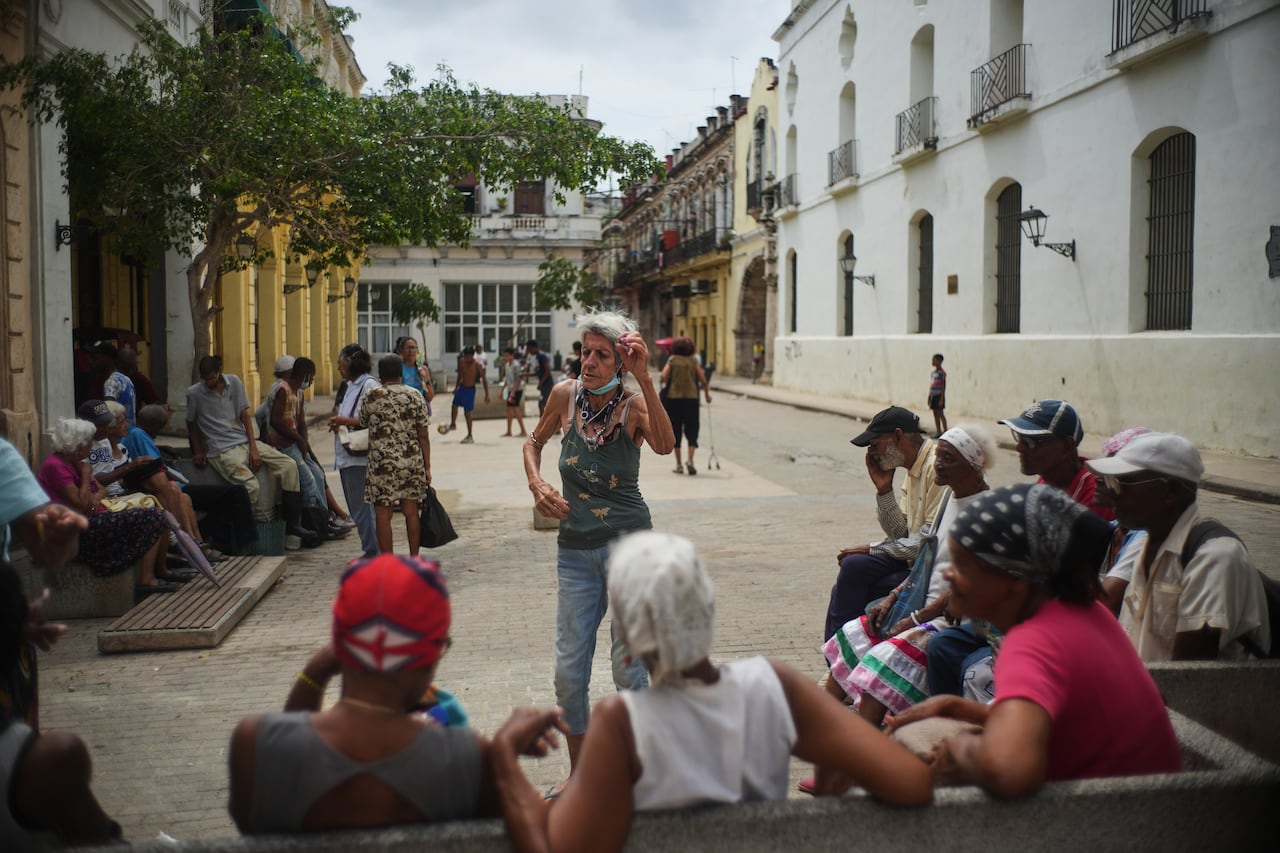 People are sitting around on the street with a woman dancing in the centre.