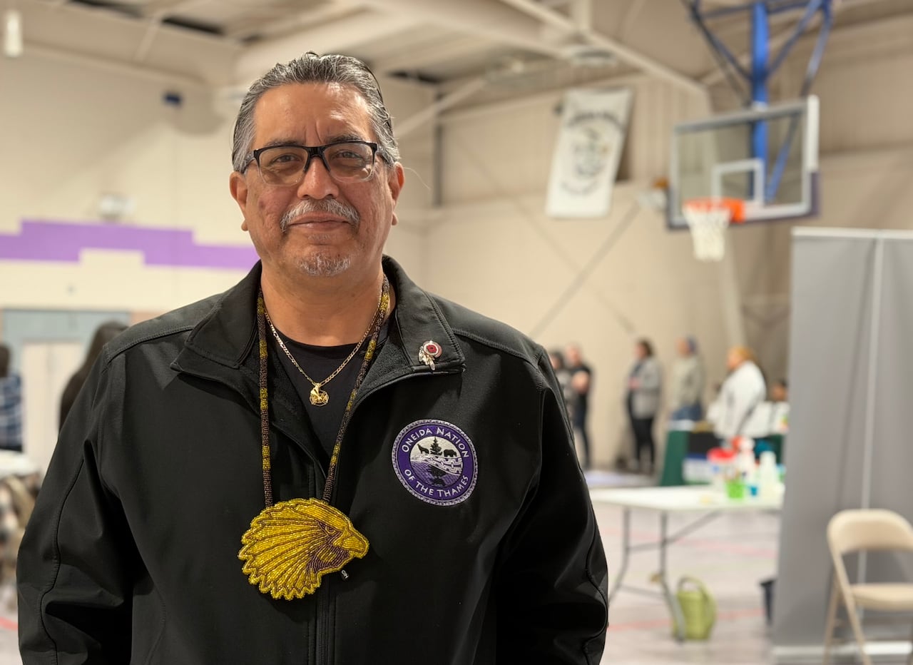 A man stands smiling at the camera, there's an event happening behind him