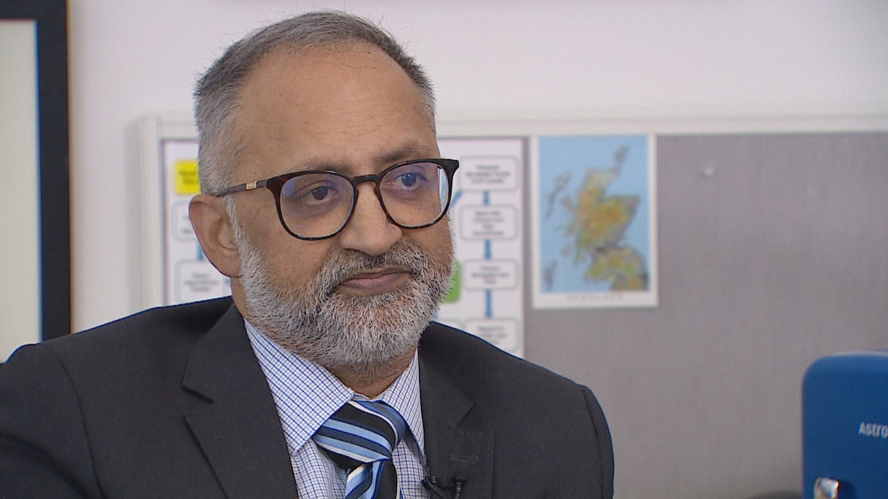 A man with a beard and glasses sits in an office.