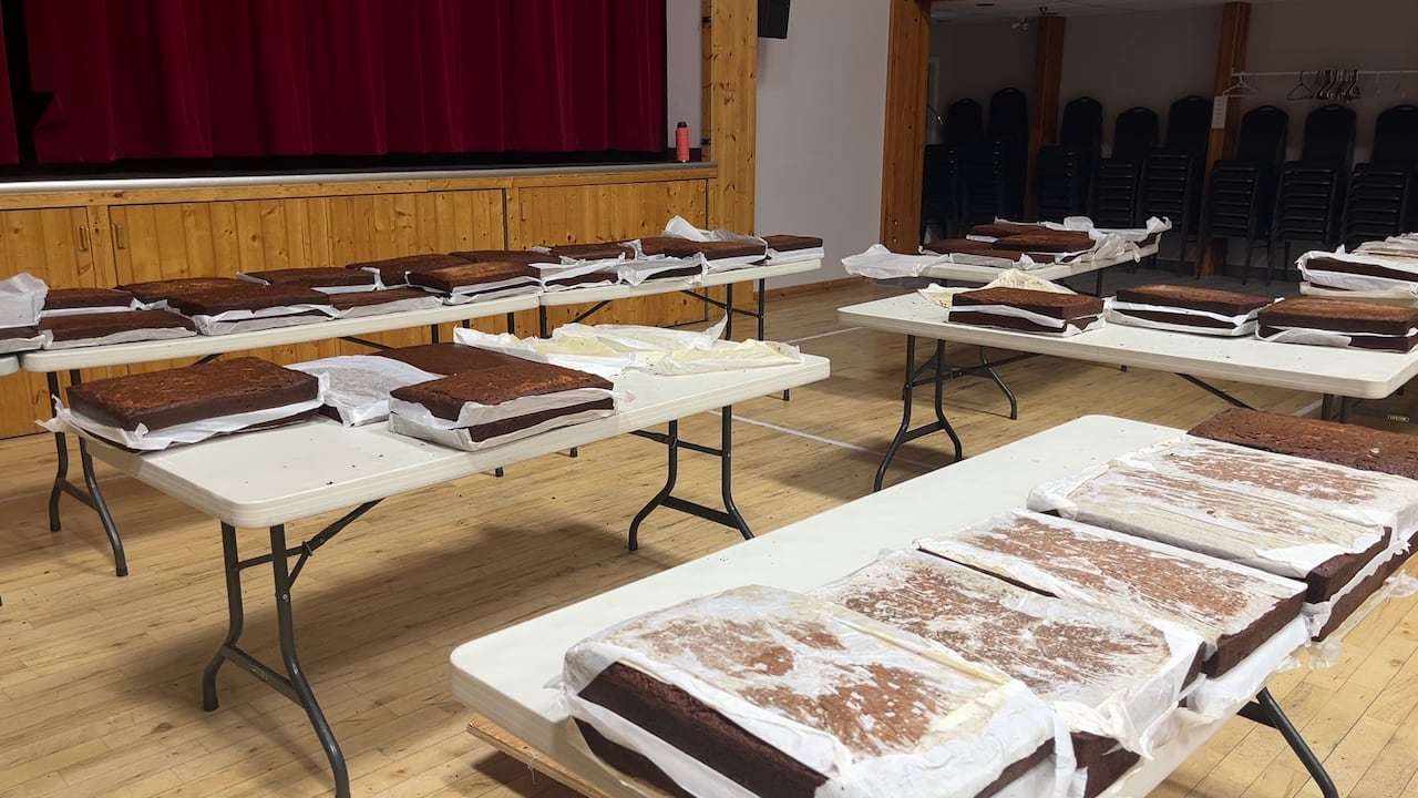 A number of cakes sit on foldable tales in a community centre.
