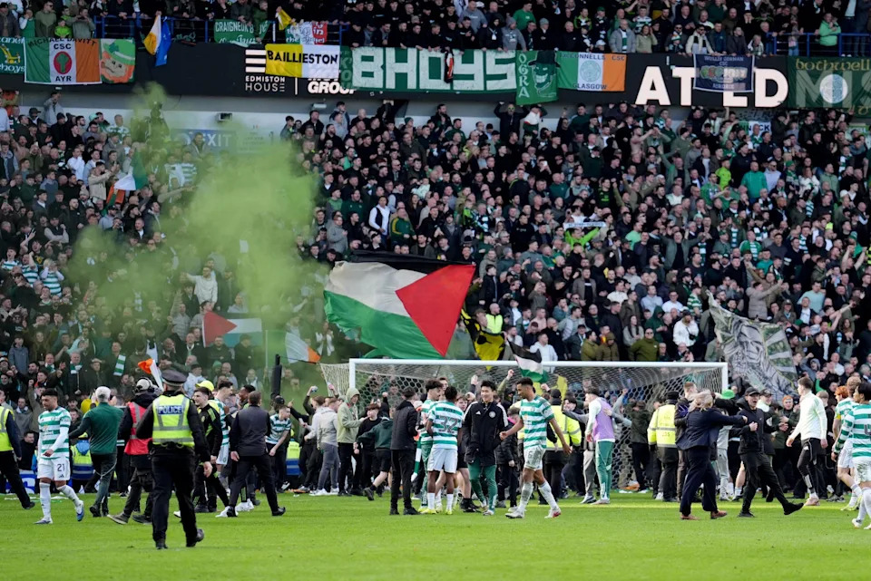 Green smoke over a stand full of Celtic fans at Ibrox - a few of the fans are waving Palestinian flags