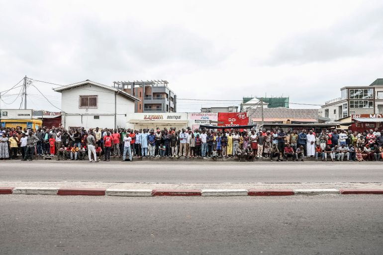 Supporters of incumbent President of the Republic of Congo and presidential candidate Denis Sassou Nguesso stand on the side of the road as they wait fot him to arrive at a polling station in Brazzaville on March 15, 2026 during the Republic of Congo's presidential elections. (Photo by Daniel BELOUMOU OLOMO / AFP)