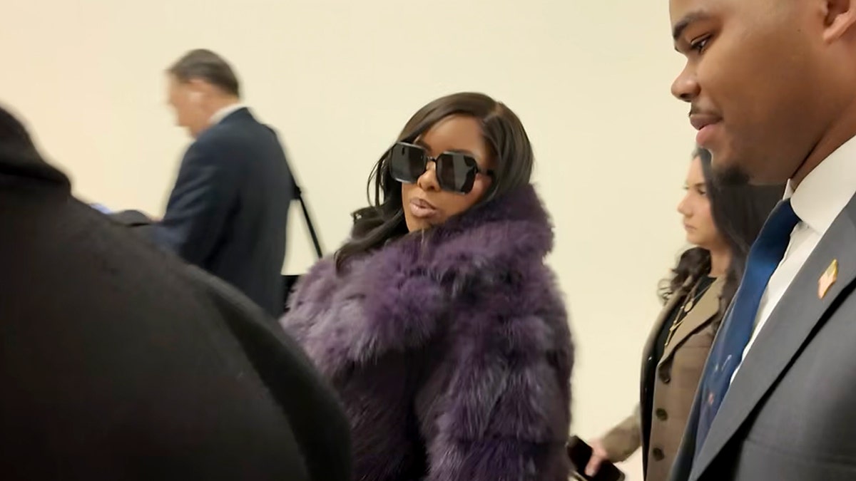 Rep. Jasmine Crockett walking out of the Capitol speaking to a reporter in fur coat and glasses