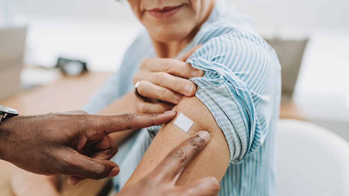 doctor puts bandaid on woman's arm