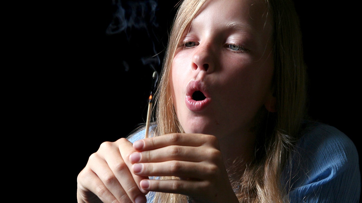 girls blows out a lit match